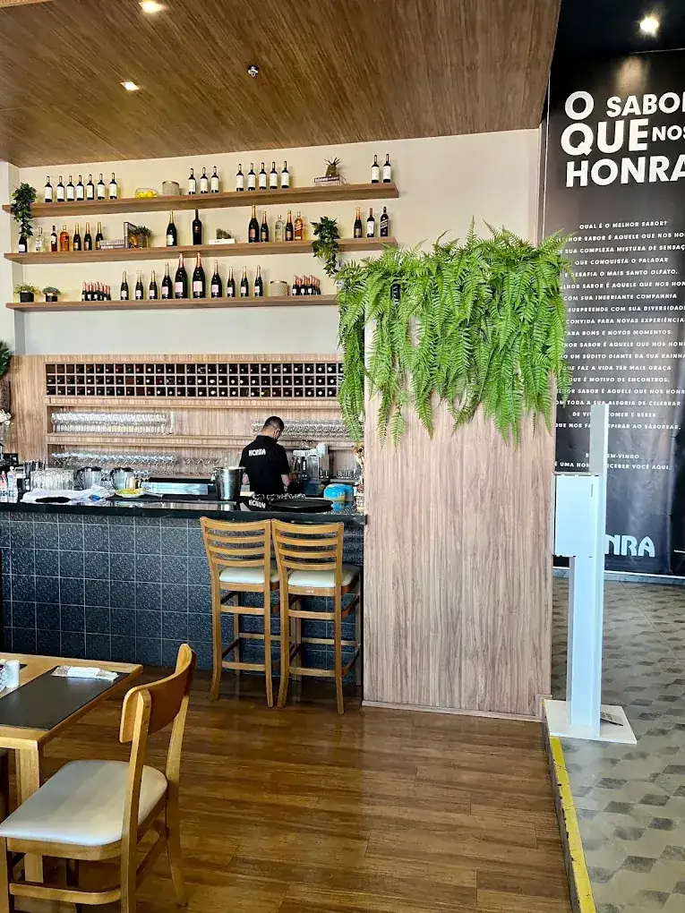 Bar com prateleiras de vinhos e parede com a frase O sabor que nos honra